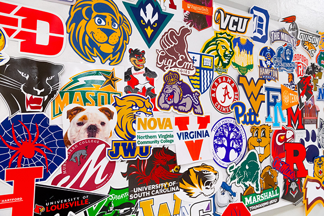 A bulletin board covered in college logos