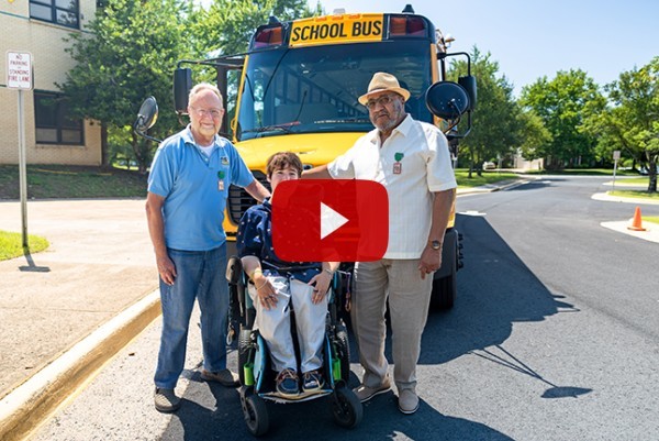 Mr. Ron, Shea Megale, and Mr. Bill in front of a school bus. 
