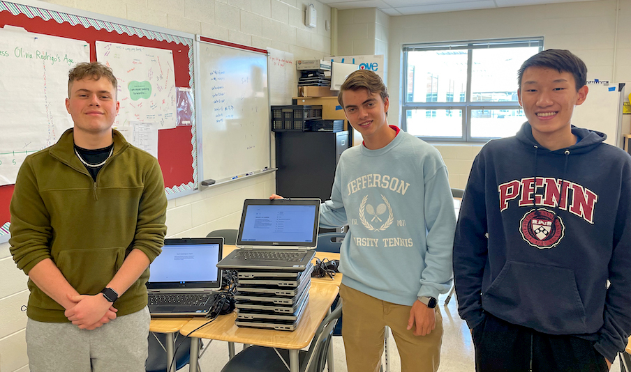 Connor Humphreys, James Henry, and Tianhao Chen pose with refurbished laptops