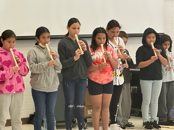 Photo of a row of fifth grade students playing the recorder in the cafeteria.