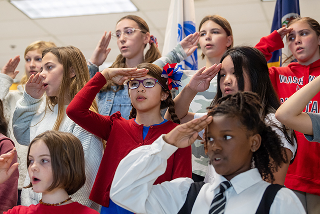 Students salute while singing