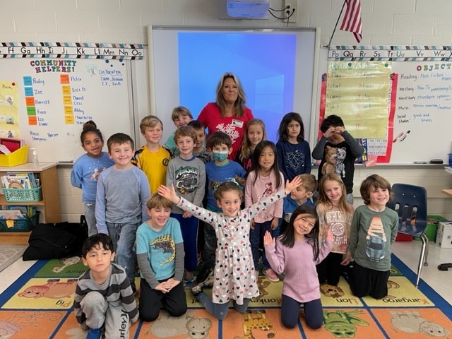 Retired teacher Mrs. Stickel poses with Ms. Crouse's first grade class. 