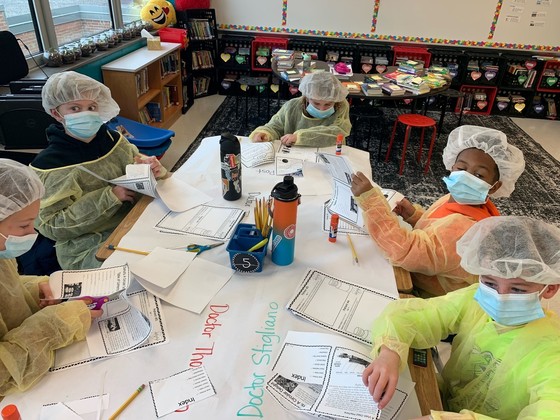 An image shows fourth graders wearing medical PPE participating in a classroom activity.