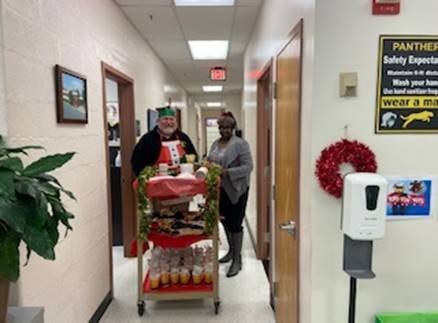 Mr. Lundy and Ms. D serving hot chocolate and doughnuts to their staff