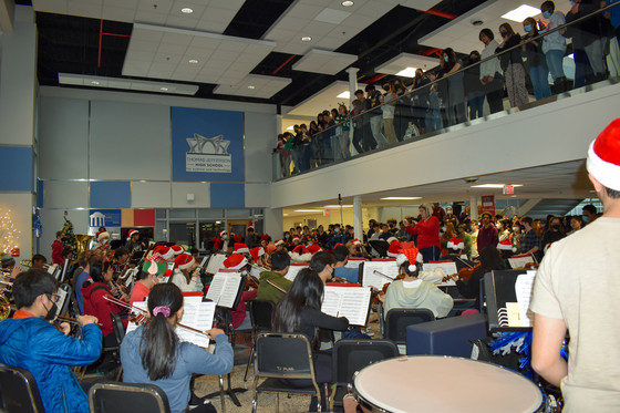 Orchestra performing in Nobel Commons with large crowd gathered.