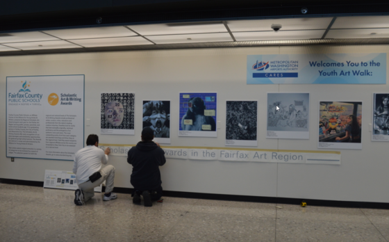 Posters of award winning FCPS Student Scholastic Art being hung at Dulles International Airport.  