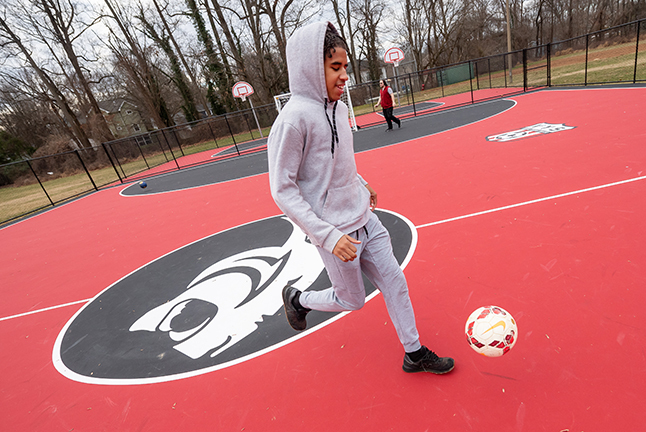 A student kicking a ball at Cedar Lane School's new Futsal court.