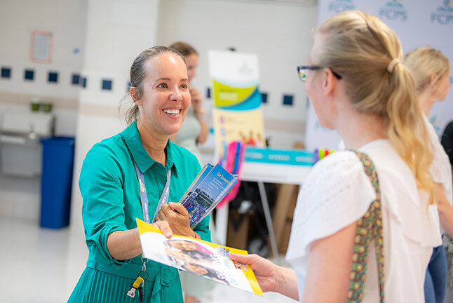 FCPS media relations personnel handing out information at an event.