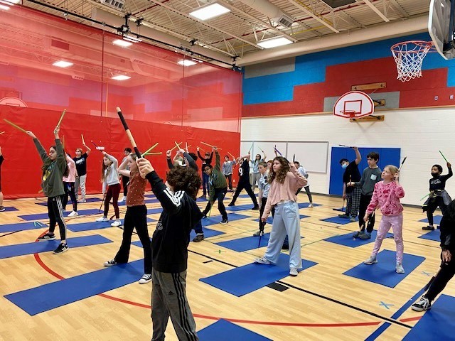An image of Clermont students participating in a yoga drumming activity. 
