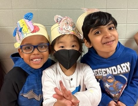 Three kindergarten students smililing wtih groundhog hats