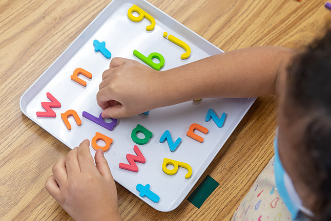 Student playing with block letters