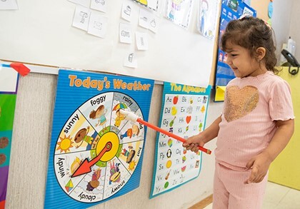 kindergarten student pointing to weather diagram