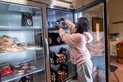 Student placing food in industrial refrigerator