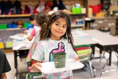 A kindergarten student holding her planted pumpkin seed