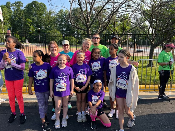 A group of girls who participated in the Girls on the Run 5K are wearing purple t-shirts and smiling.