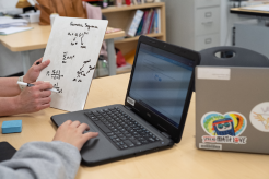 teacher working with student on laptop