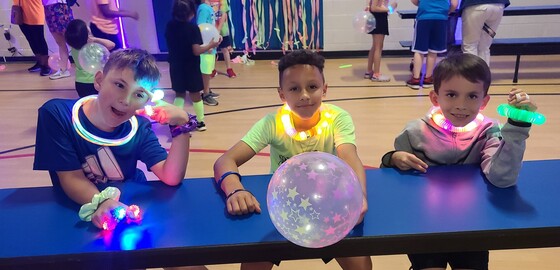 Students wearing glowing clothing at PTA Glow Dance