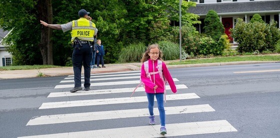 Student crossing crosswalk near crossing guard