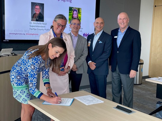 Amy Alley, Executive Director of Think Big for Kids signs Ignite Partnership flanked by Superintendent Reid and others.