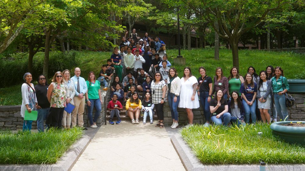 Navy Federal Credit Union employees who and their Thoreau Middle School pen pals in an outside group photograph.