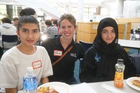 A Navy Federal Credit Union volunteer enjoying lunch with two Thoreau Middle School students.