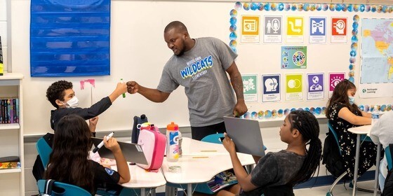 teacher fist bumping student in classroom