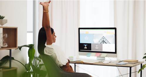 Person stretching their arms and sitting at their computer desk