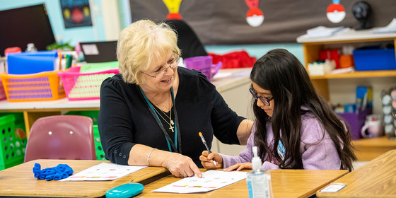 teacher helping student at a desk