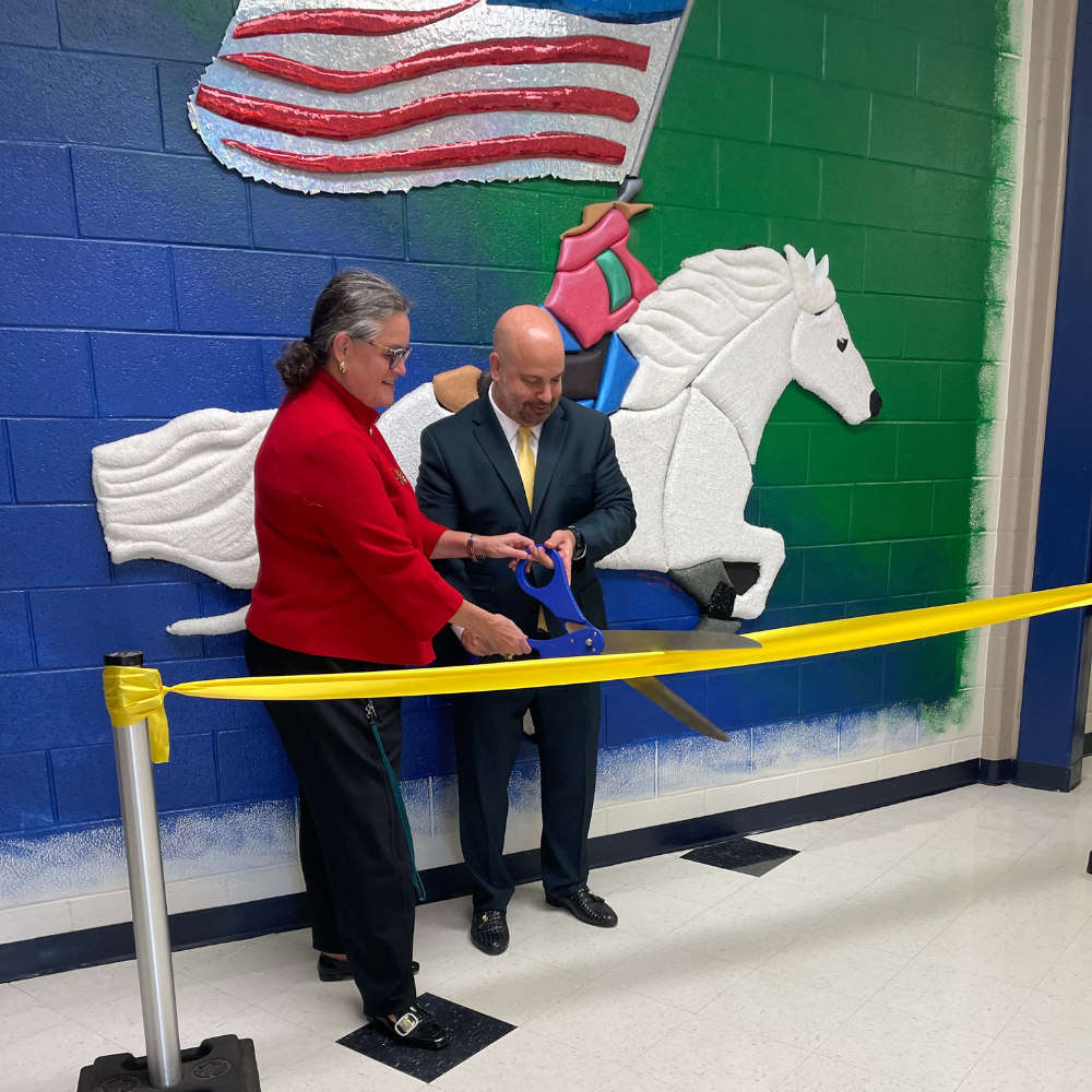 Dr. Reid and South County Principal Dr. Khoshaba cutting ribbon in front of Sensory Stallion mural
