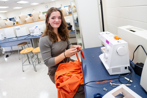 A student sews a zipper at a sewing machine