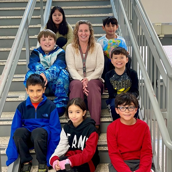 Principal Salata poses with some third grade students on the stairwell. 
