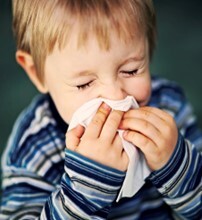 child blowing his nose with a tissue