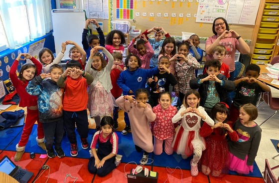 Class picture of students making heart sign