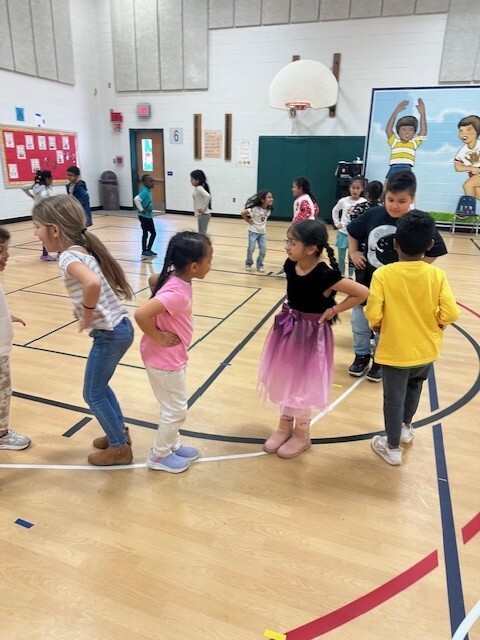 Students dancing in a circle in the gym while they get ready for Heritage Festival