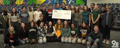 Students and teachers standing together holding large check