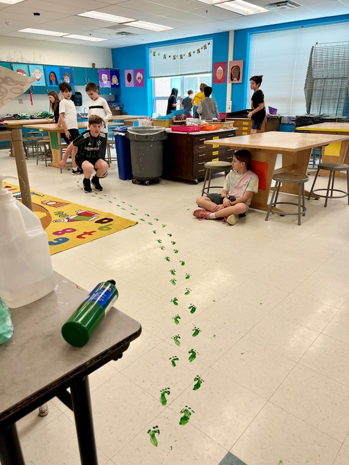 Small green footprints trail along the floor in the art room.