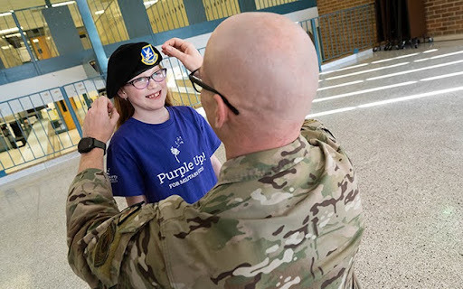 father puts his military hat on his child