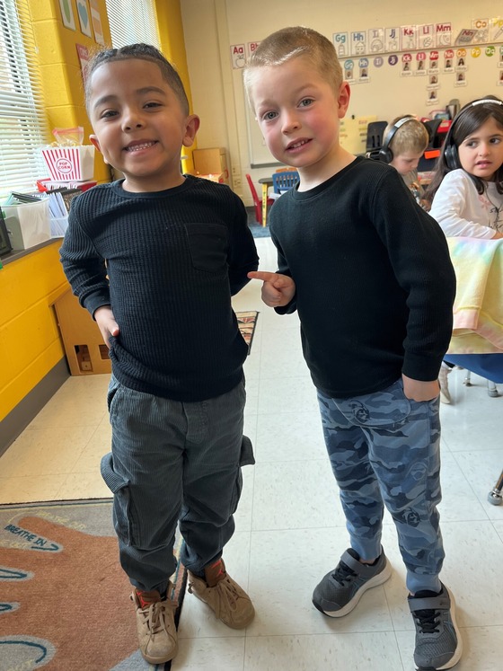 Two kindergarten students smile and pose in similar outfits.