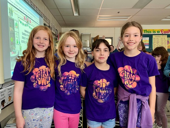 Third grade girls wear matching purple shirts that say, "Girl Power"