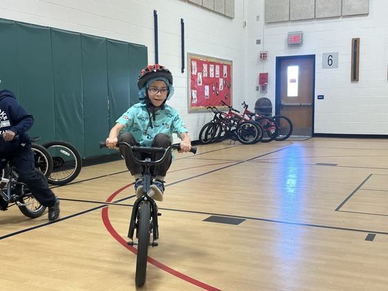 A student riding a bicycle in the gym