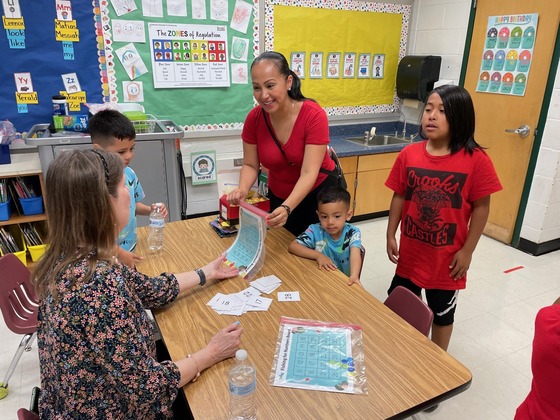 A teacher handing materials to a family at Family Learning Night