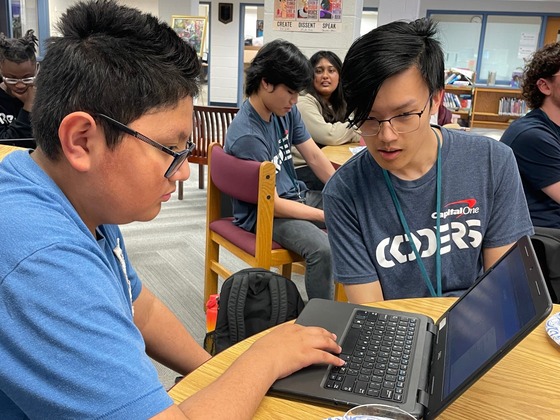 A Capital One volunteer working with a Whitman Middle School student on a computer coding project.