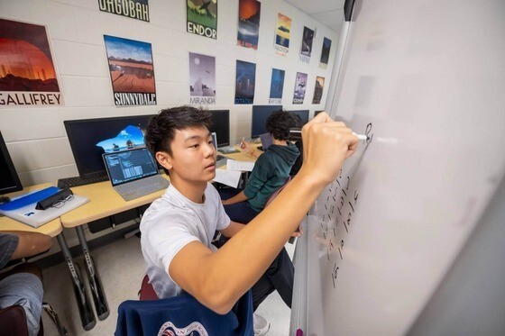 Student working on math problem at white board