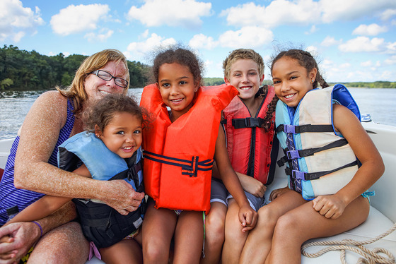 photo of lady and four children wearing life vests on a boat