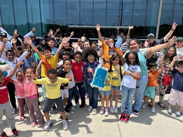 A group of children and their families posing in front of the Udvar-Hazy Air & Space Museum