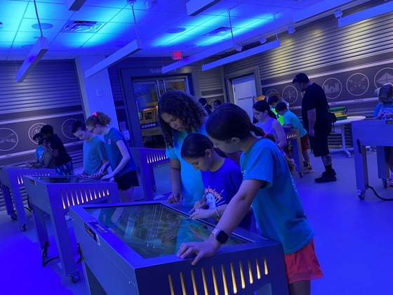 Fifth graders in a room with blue lighting participate in activities at the National Museum of the United States Army.