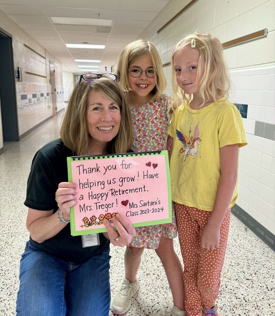 Paula Treger, counselor, poses with a student holding a sign that says "Thank you for helping us grow"