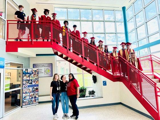 Graduating seniors who attended Clermont Elementary pose on a red staircase.