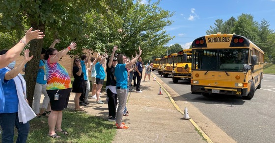Staff waving goodbye to students on the buses