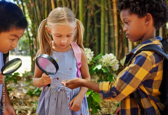 Children standing outside holding magnifying glasses